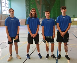 czterej zawodnicy stoją z rakietami w sali gimnastycznej