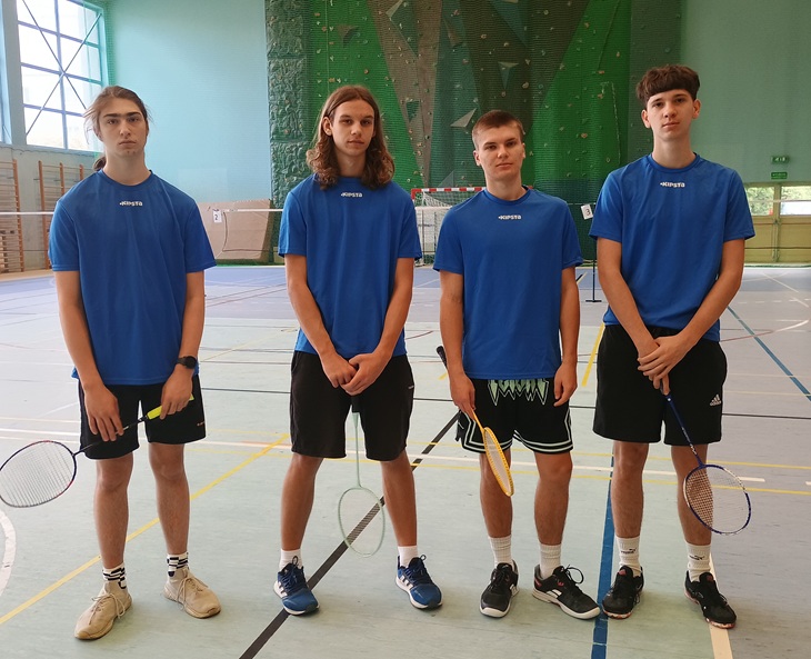 czterej zawodnicy stoją z rakietami w sali gimnastycznej