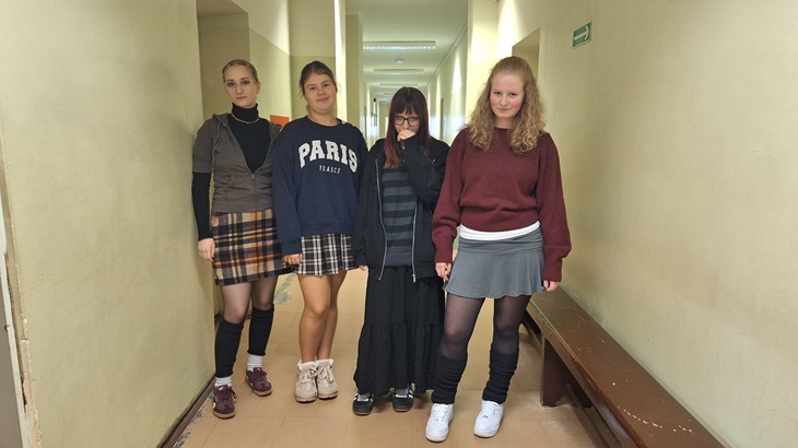 cztery dziewczyny stoją w korytarzu w spódnicach