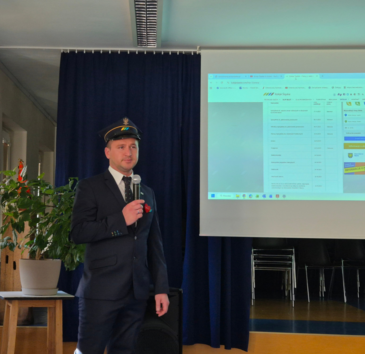 kolejarz w mundurze wygłaszający prelekcję w auli szkolnej podczas tygodnia przedsiębiorczości