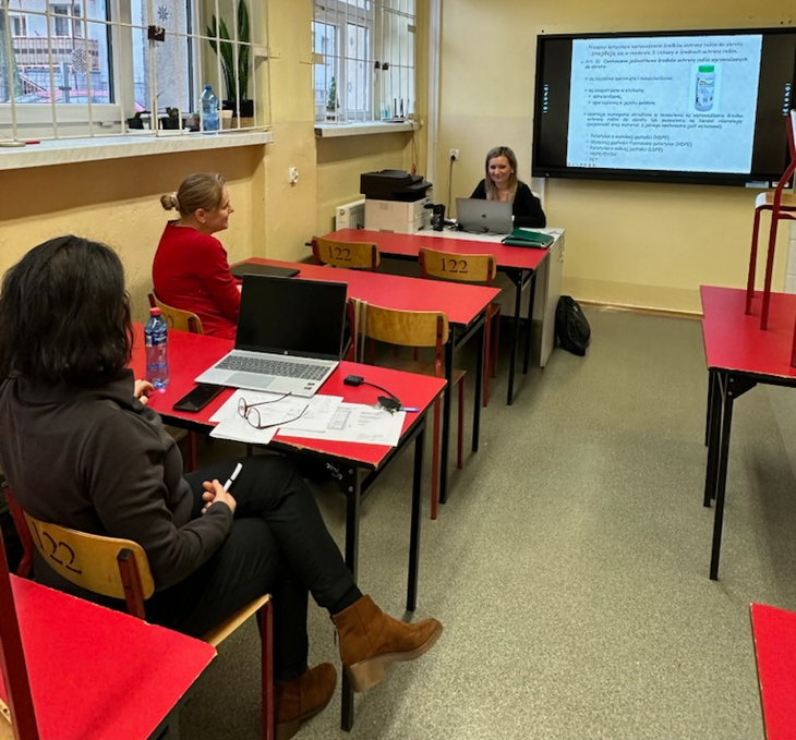 w sali lekcyjnej odbywa się szkolenie. Widać dwie słuchające kobiety i trzecią, która prowadzi zajęcia