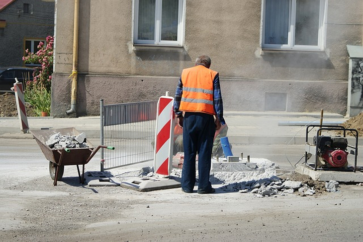 prace drogowe i robotnik, który je wykonuje stojący tyłem