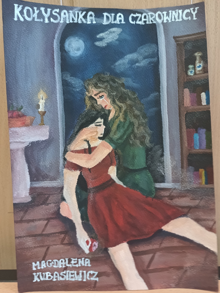 Na zdjęciu widać ilustrację lub obraz z tytułem „Kołysanka dla czarownicy”. Przedstawia on dwie kobiety w mrocznym, nocnym wnętrzu – jedna z nich trzyma na kolanach drugą, która wygląda na osłabioną lub nieprzytomną. Scena rozgrywa się przy oknie, za którym widać księżyc i nocne niebo.  W pomieszczeniu znajduje się także świeca oraz półka z książkami i butelkami, co nadaje całości tajemniczy, nieco magiczny klimat. Na dole widnieje podpis autora: Magdalena Kubasiewicz.