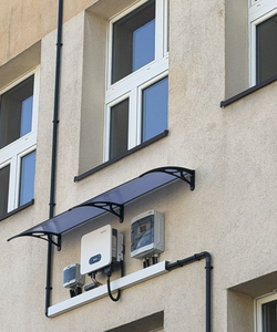 Na zdjęciu widoczny jest element instalacji fotowoltaicznej zamontowany na elewacji budynku wraz z urządzeniami sterującymi i zabezpieczającymi. To przykład nowoczesnych rozwiązań z zakresu odnawialnych źródeł energii, wykorzystywanych w praktycznej nauce i edukacji technicznej.